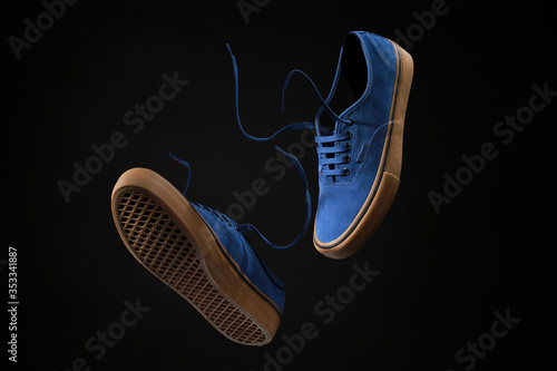 Close up view of levitation blue sneakers shoes with flying laces over black background with copy space for text. 