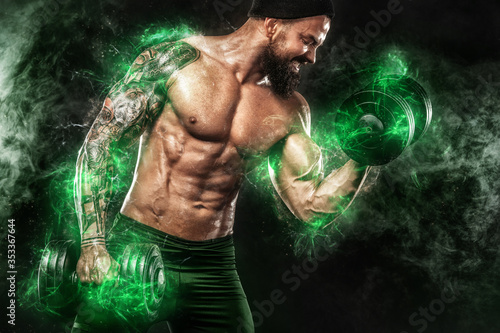 Athlete in green energy lights. Muscular young fitness sports man bodybuilder doing workout with dumbbell in fitness gym