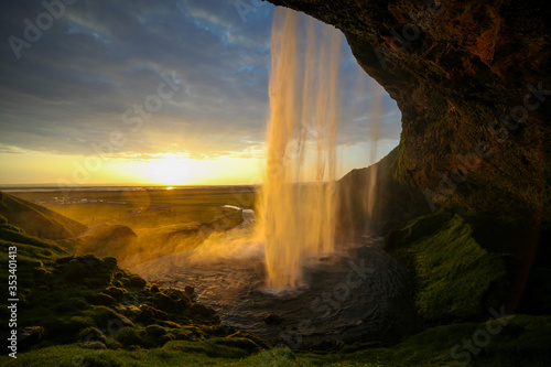 Waterfall Selandjafoss Iceland at sunset or sunrise. Beautiful waterfall in Iceland. Golden hour. Cave and waterfall. Travel in Iceland. Beautiful sky against the big waterfall. inside the water. 