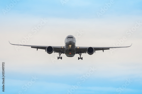 A heavy passenger airplane on final approach on a cloudy day.