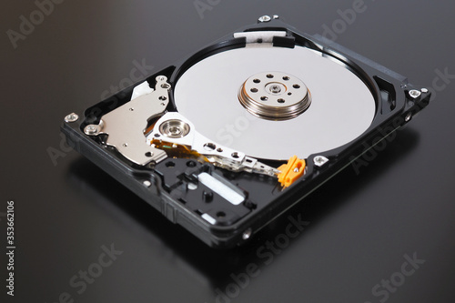 A disassembled open hard disk drive HDD of a computer or laptop lies on a dark matte surface. Close-up. IT&C. Illustration: computer hardware and equipment. Macro