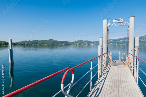 Modern steel pier on the lake for tourist boats. Lake Maggiore at the lakefront of the town of Ispra, northern Italy, with on the left the park of the Golfo della Quassa