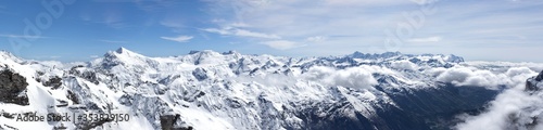 Panoramic landscape photography of snow-capped mountains in Switzerland. Snowy mountain tops banner. Beautiful view from above of snowy mountain peaks with clouds below the horizon