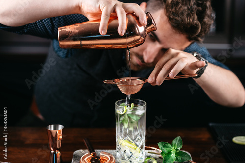 Expert bartender and barman pouring and preparing mojito cocktails