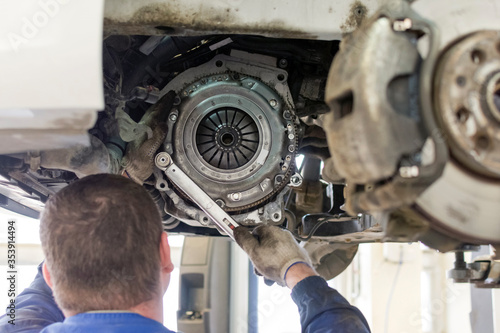 Car repair in a car service. Replacing the clutch disc of a gearbox on a car at a service station. Hands of a professional car mechanic. Cars repair technology. Technical photography.