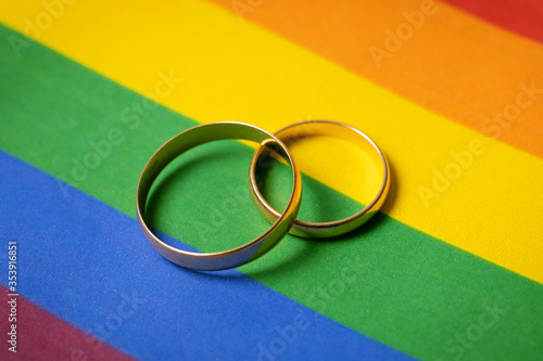 same-sex marriage concept - two wedding rings on lgbt rainbow flag