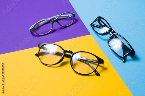 several pairs of glasses lie on a colored background, glasses for adults and children, top view, copy space, focus in the foreground