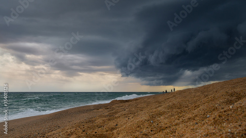Storm clouds over the sea and people on the beach.