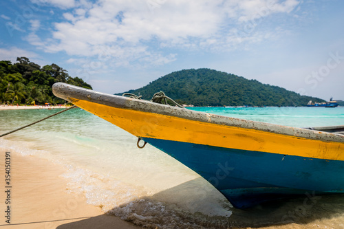 Boat at beautiful tropical beach with white sand, palms and turquoise water on Perhentian Island, Malaysia