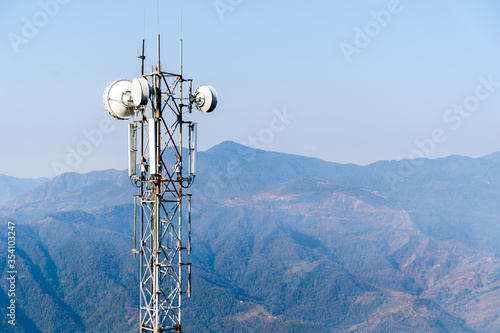 Telecommunication tower with antennas. Wireless Communication Antenna Transmitter with Mountains on Background. Stock Photo.