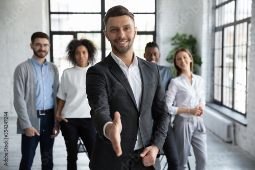 Head shot portrait confident smiling businessman offering hand for handshake, looking at camera, friendly hr manager team leader welcoming new worker, making agreement or great deal