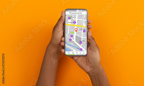 African American girl holding cellphone with map and restaurant navigation pointers, orange background. Collage