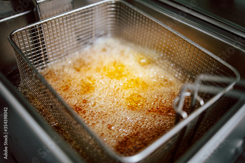 Close-up of fries in deep fryer. Restaurant meal preparation, side dish