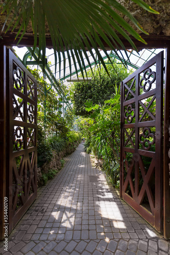 Otwarte, ażurowe drzwi prowadzące do korytarza palmiarni