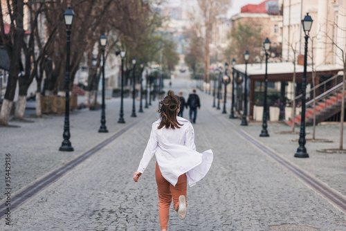 girl or woman in a white medical coat runs away along the street. doctor, nurse runs around the city. coronavirus, disease, infection, quarantine, covid-19