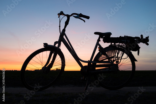 Bicycle is silhouetted against a colorful evening sky after sunset