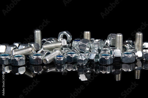 metal hardware bolts and nuts on black background with reflection