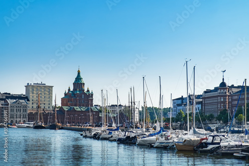 Scenic Finnish cityscape of Scandinavian Old Town pier with Uspenski Cathedral, old boats and sailing ship in sea harbor. Katajanokka district is famous tourist destination in Helsinki city, Finland
