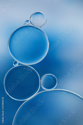 Macro of oil and water bubbles creating a scientific image of cell and cell membrane in blue in a vertical format.