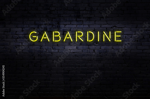 Neon sign. Word gabardine against brick wall. Night view