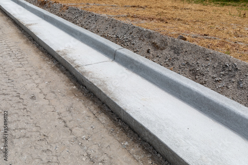 Road construction details, extruded concrete curb beside freshly prepared road bed, horizontal aspect