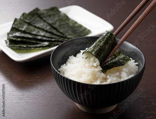 Wrapping nori around rice set against a wooden backdrop.