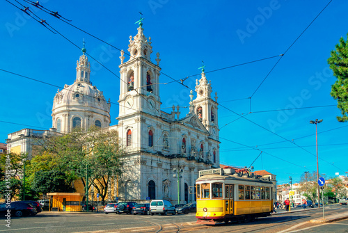Estrela Basilica or the Royal Basilica is an ancient carmelite convent in Lisbon, Portugal. Vintage yellow tram on the old streets of Lisbon. Famous landmarks of Lisbon.