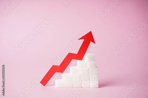 Increase in blood sugar levels, the graph of growth of the sugar cubes and arrow on top on a pink background, close-up. Diabetes concept.