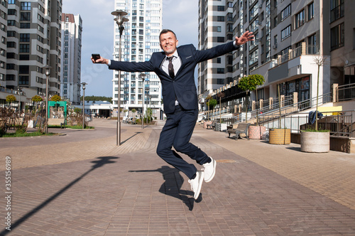 young businessman in a blue suit jumping in the air against blue sky