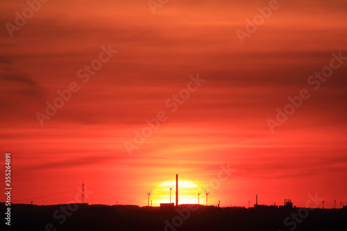 Silhouette einer Industrielandschaft vor roter Sonne