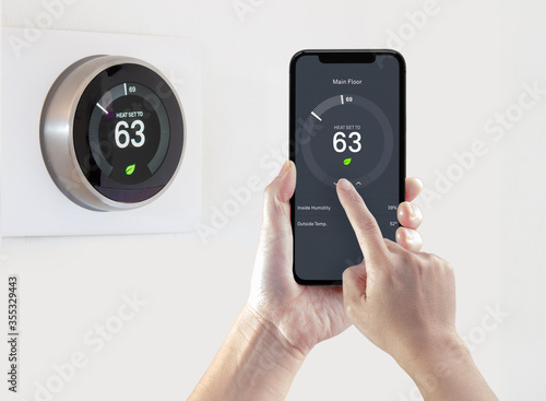 A person using a smart phone application saving energy with a wireless smart thermostat on a white background.