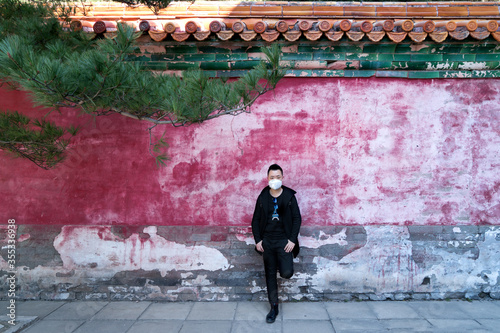 Handsome guy wearing a mask in front of the red wall in Beijing Summer Palace