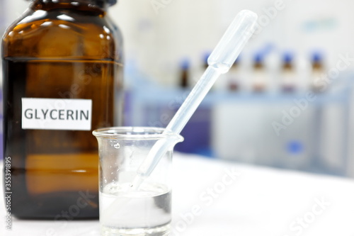 Glycerin in glass beaker and brown amber bottle inside laboratory with copy space.