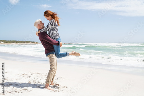 Senior man lifting mature woman on beach