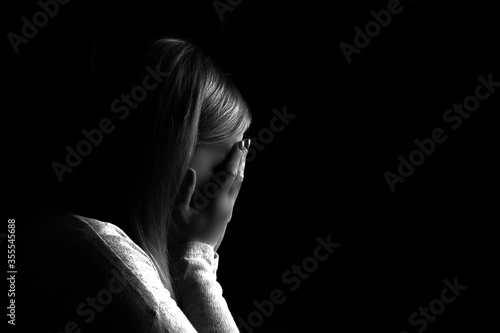 Black and white portrait of a woman hiding her face with hands. Stop violence against woman or mental health concept. Studio shot.