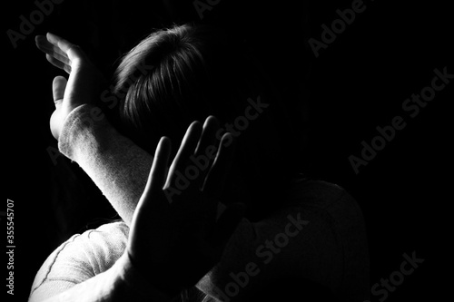 Black and white portrait of a woman hiding her face with hands. Stop violence against woman or mental health concept. Studio shot.