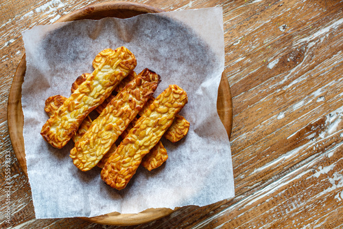 Fried tempeh or tempe, traditional Indonesian soy product, on a wooden tray. Top view. With space.