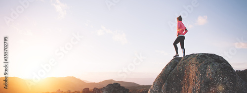 Athletic woman resting during training watching the sunset and mountain landscape. Sport tight clothes.
