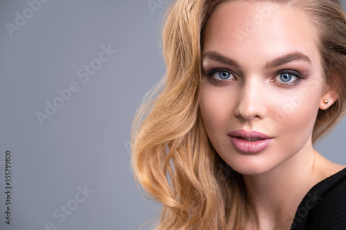 Beautiful face of an attractive model with blue eyes. Woman with beauty long brown hair and natural makeup. Closeup portrait of a caucasian female. Attractive fashion model. Beauty face of a blonde