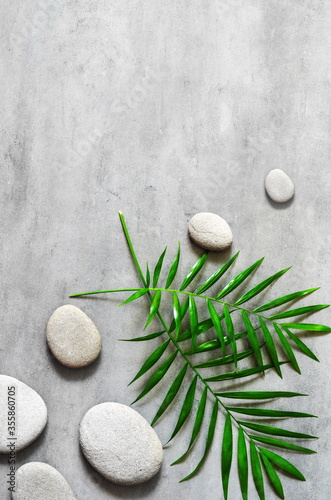 Flat lay composition with spa stones, palm leaves on grey background.