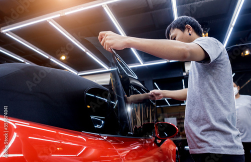 Applying tinting foil on a car window in a auto service