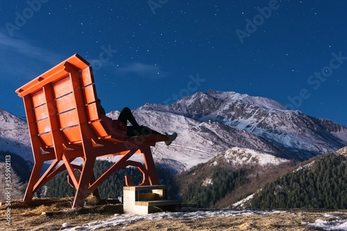 Women siting on big bench in mountains Prato nevoso resort at night in Piedmont Alps Italy