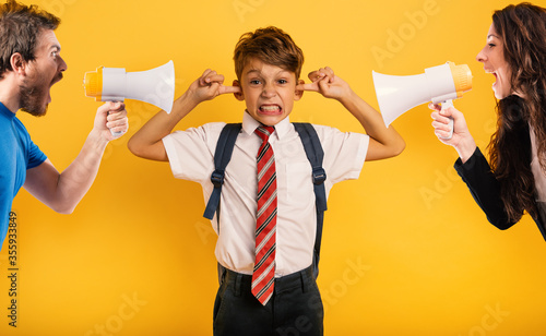 Student Child covers his ears because he does not want to hear reproach of the parents. Yellow background