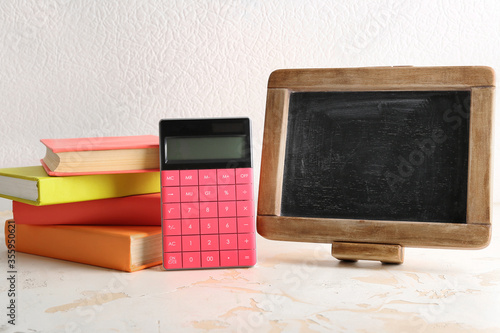 Books, calculator and chalkboard on table