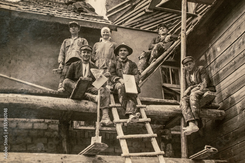 Latvia - CIRCA 1920s: Photo of builders working on site. Sitting on scaffolding. Archive vintage black and white photography