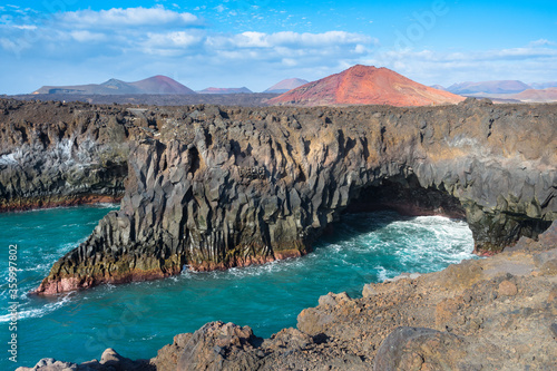 Beautiful view of Los Hervideros with Red Mountain Volcano (Montana Bermeja Volcan) in the background - Lanzarote, Canary Islands, Spain