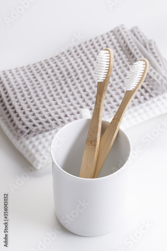 natural eco friendly toothbrush with wooden bamboo handle in a white cup