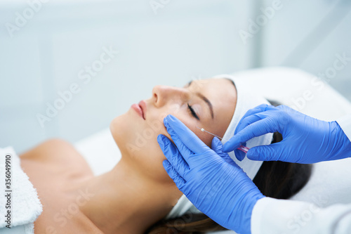 Beautiful young woman getting polydioxanone thread lifting at beauty salon.