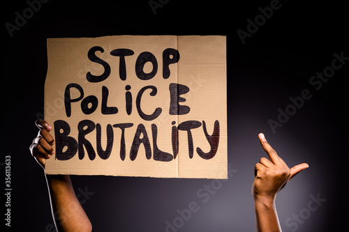 Close up photo of afro american hand hold banner stop police brutality show fuck symbol ignore haters fight rights isolated over black color background