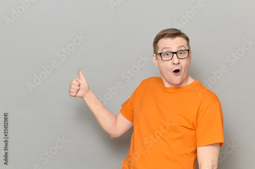 Portrait of amazed impressed man raising thumb up in approval gesture